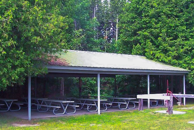 Events pavilion under the trees with open sides and picnic tables